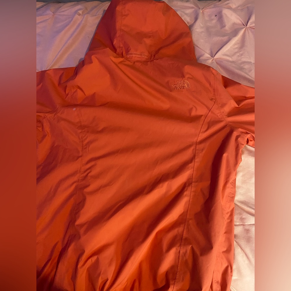 This is a coral pinkish/orangish North face rain jacket. Size Medium in Women’s.